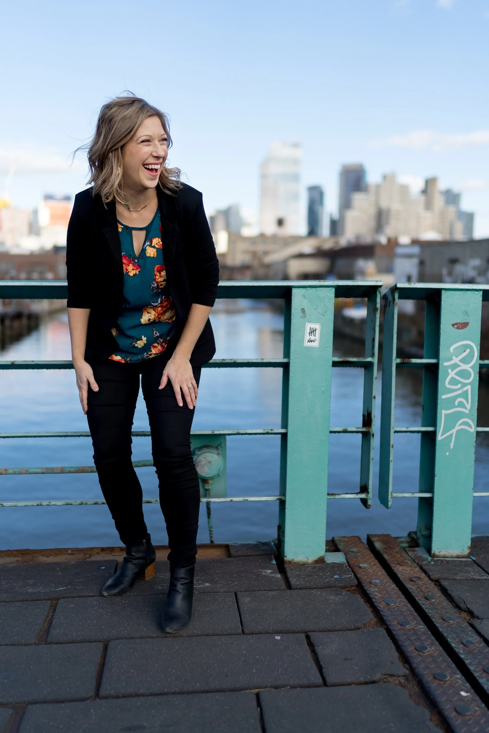 Sarah bending over laughing as she stands on a bridge over water