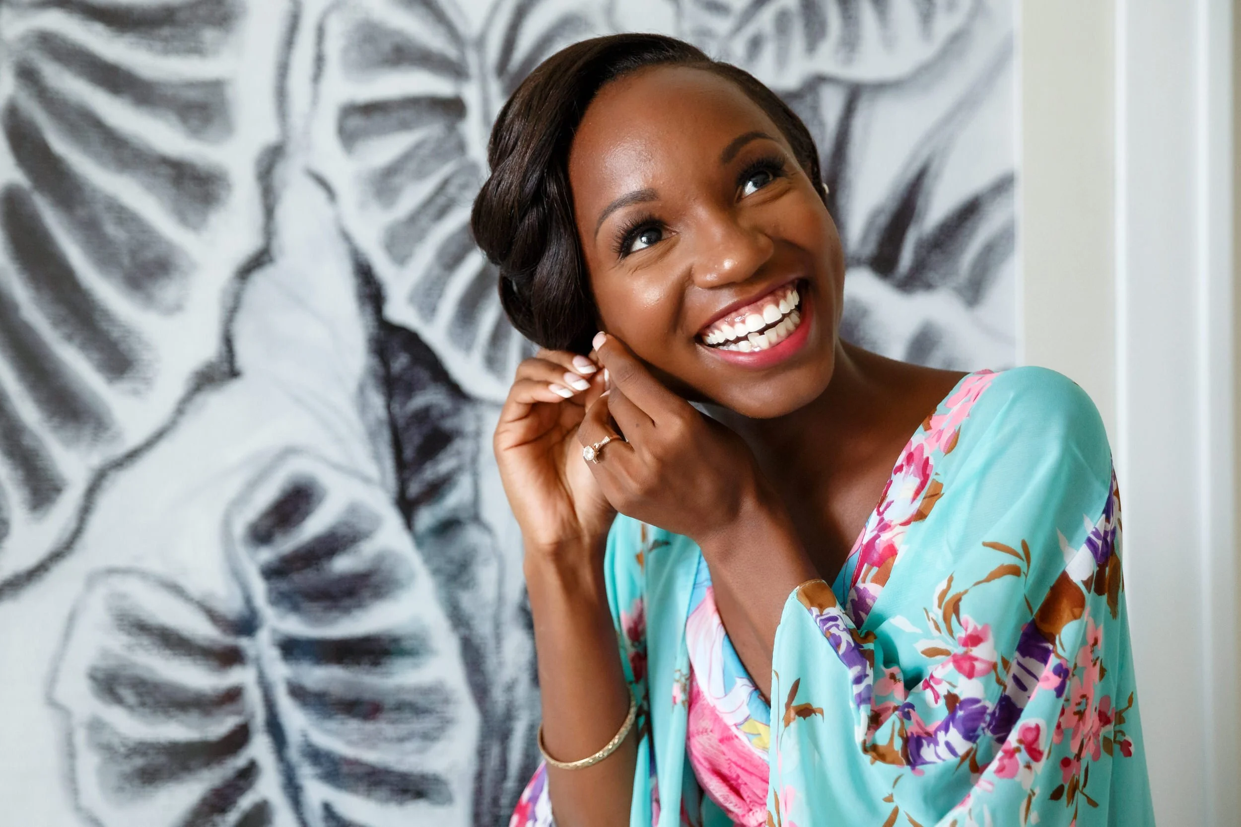 A person smiling and putting on an earring 