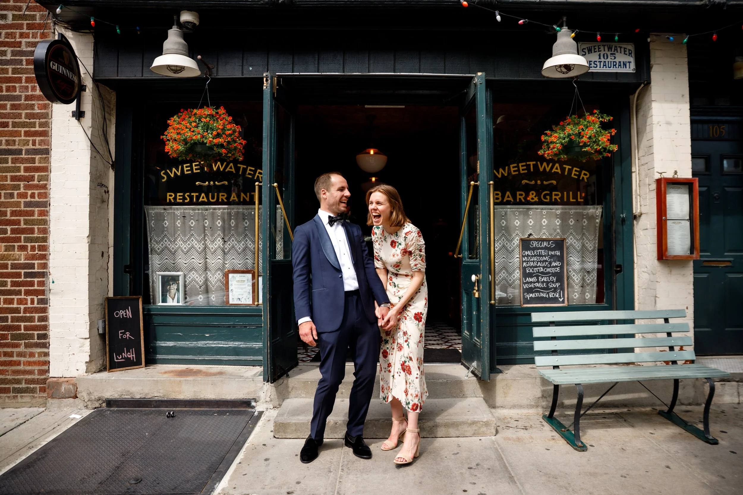 A couple laughing and holding hands on a city sidewalk