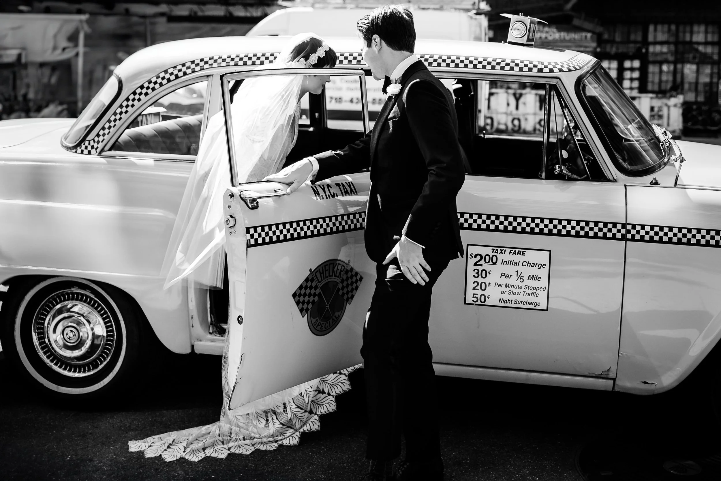 A newlywed holding a taxi door open as their partner gets in 