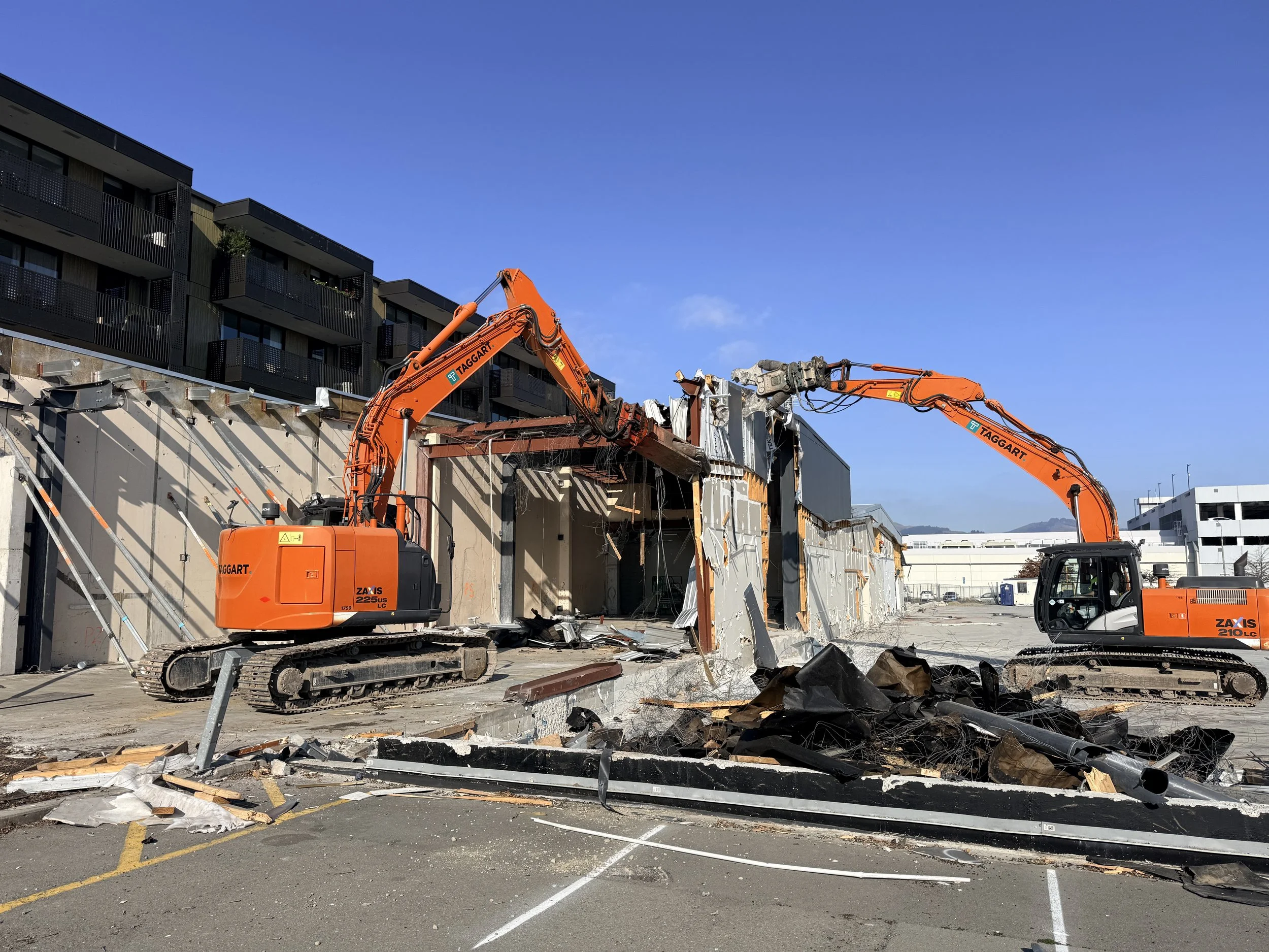 Two orange diggers demolishing a commerical building