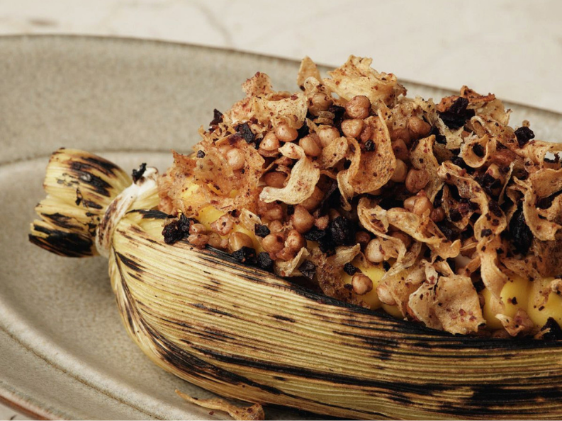 Baked stuffed banana with crispy topping and cheese, served on a ceramic plate.