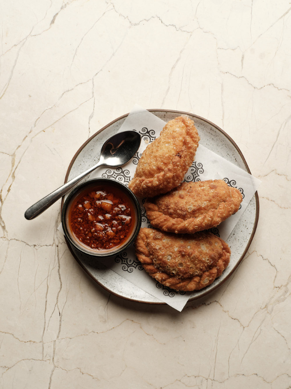 Freshly made empanadas served with dipping sauce at Santanera Bali's rooftop