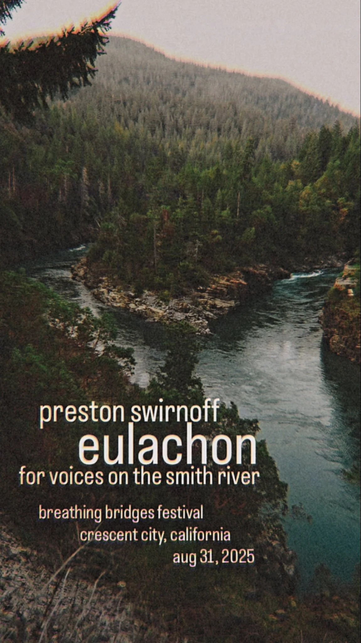 A scenic view of the Smith River flowing through a lush, green forested canyon with mountains in the background.