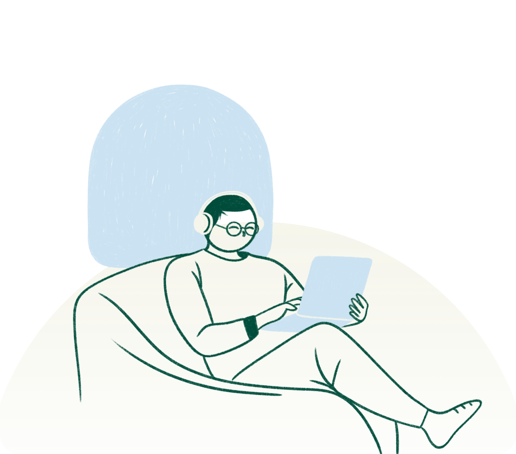 Person wearing glasses and headphones, using a laptop while sitting on a bean bag chair with a blue pillow behind them.