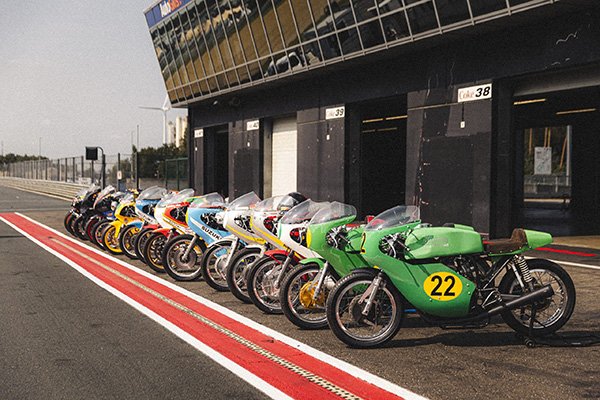 Row of vintage racing motorcycles in the pit lane at Circuit Zolder