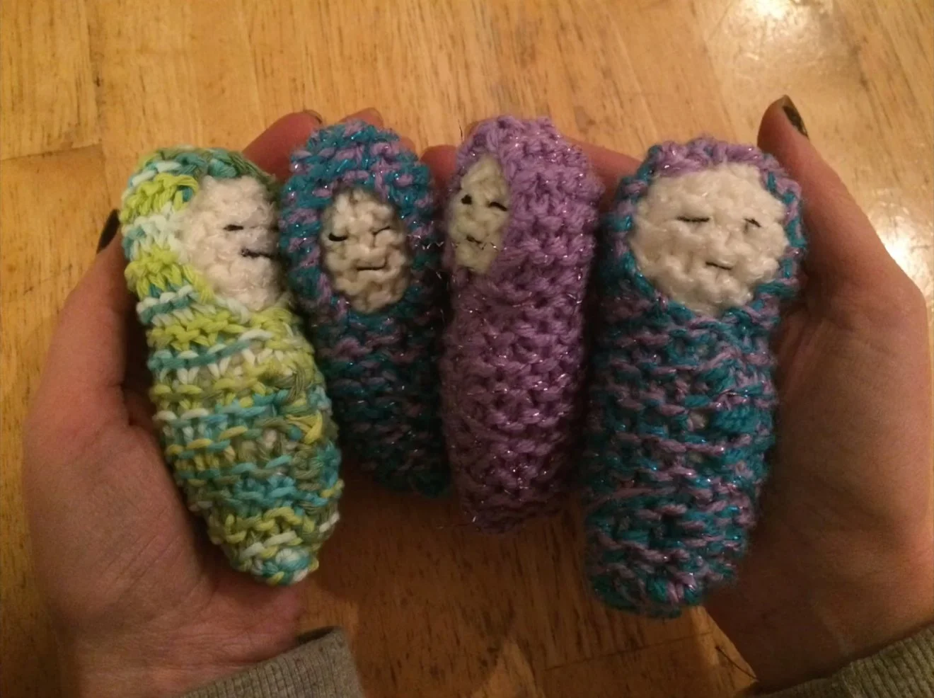 Four simple knitted Bábóga held by hand.