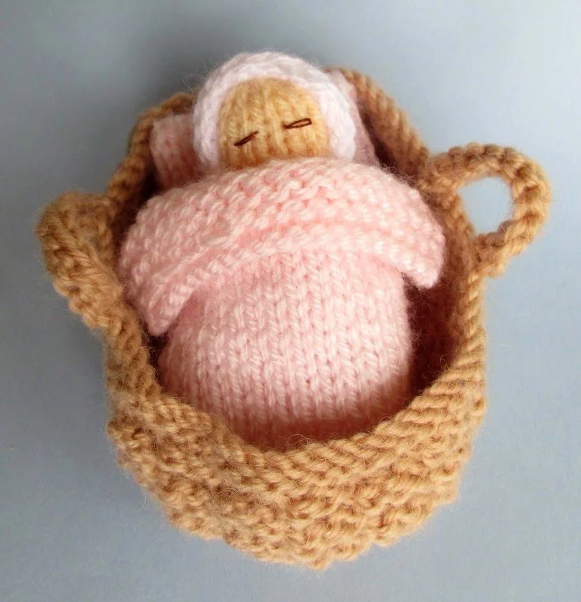 Knitted baby in a Moses basket crib.