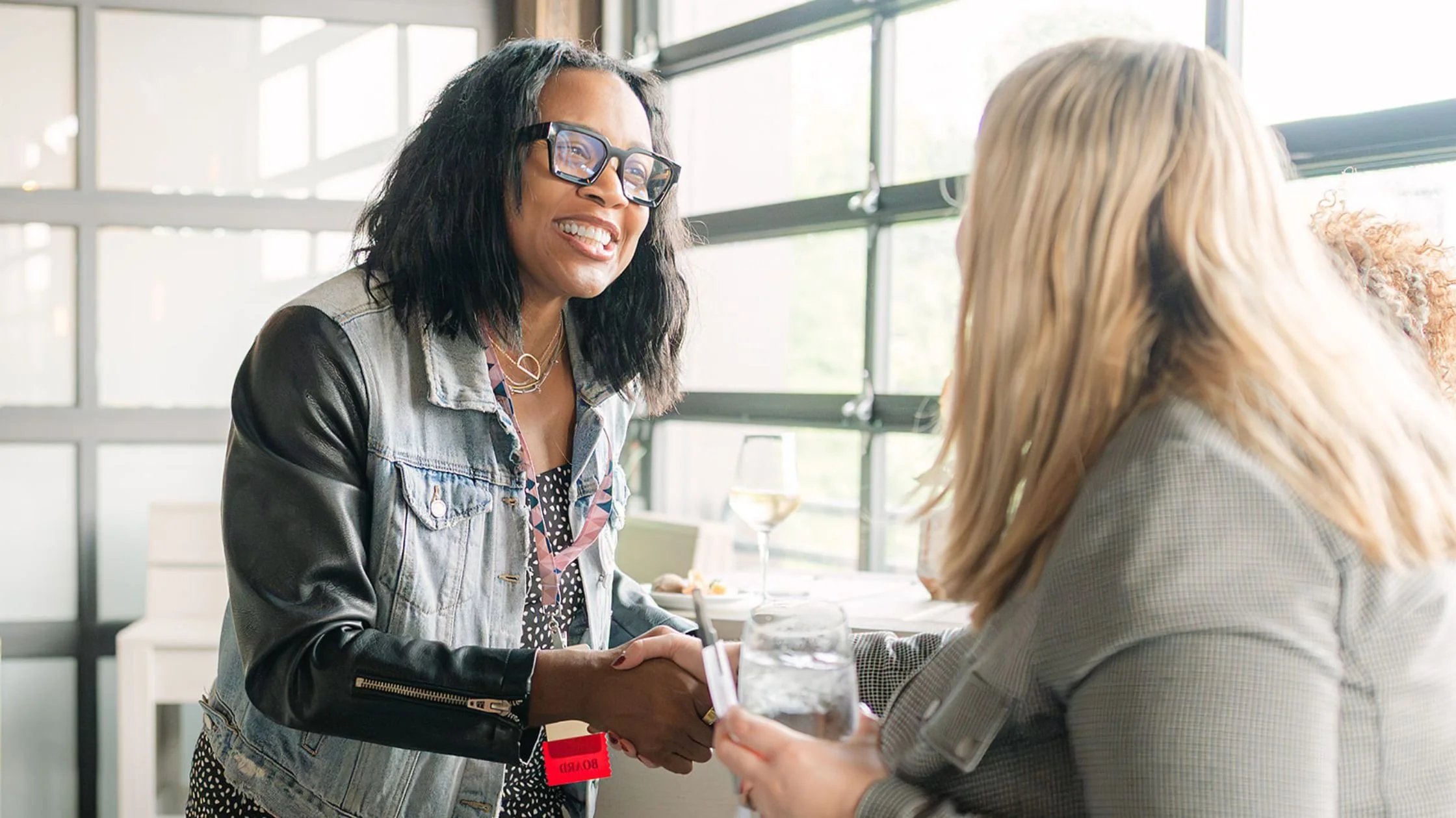 Two women shaking hands while networking at a Heels & Handshakes women in business event in Nashville.
