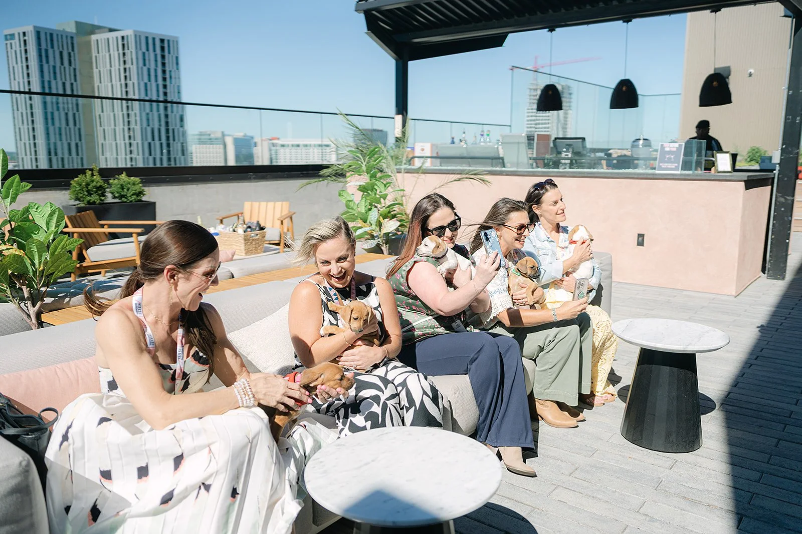 Women enjoying rooftop networking and puppy cuddles at a Heels & Handshakes community event in Nashville.