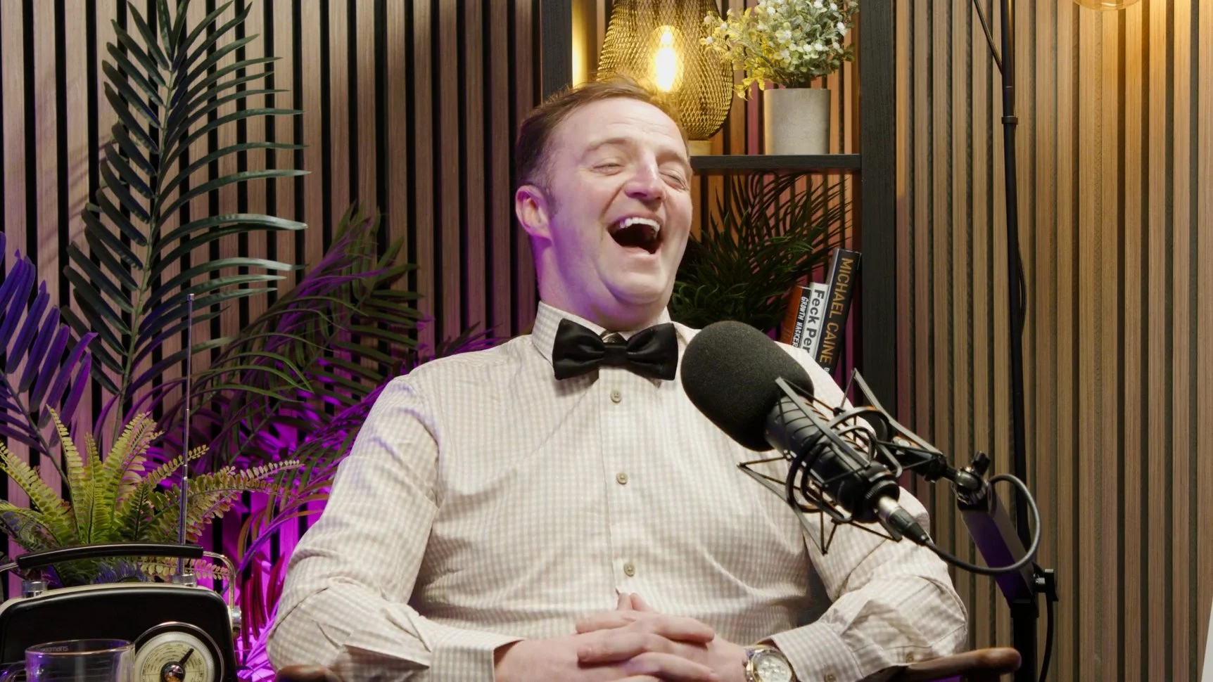 a photo of a man laughing while recording a podcast