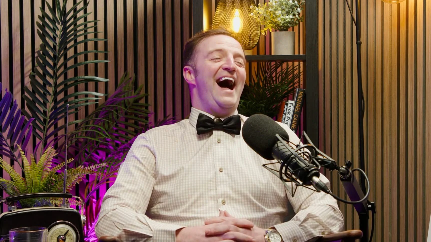 a photo of a man laughing while recording a podcast
