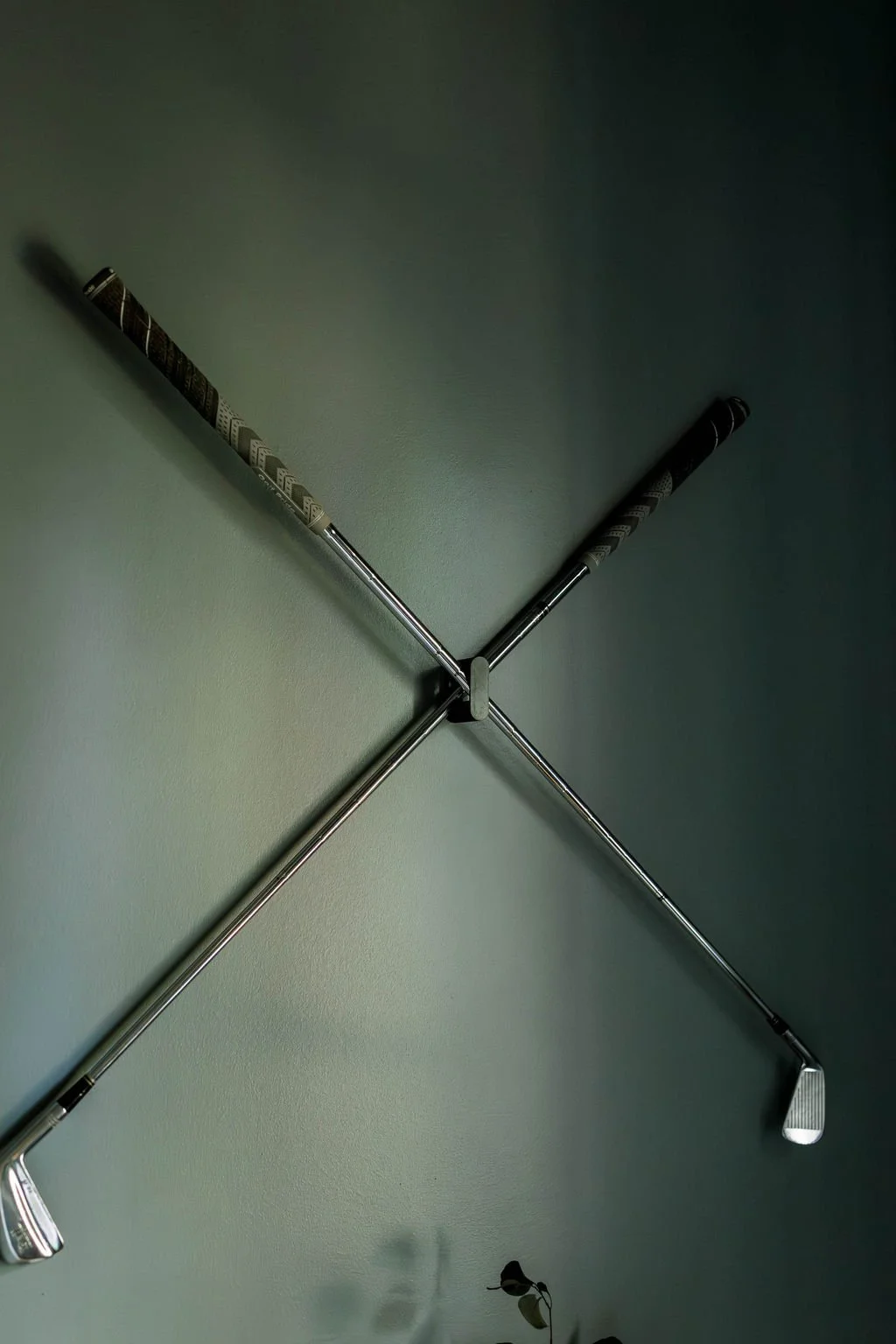 Two golf clubs crossed on a green wall.
