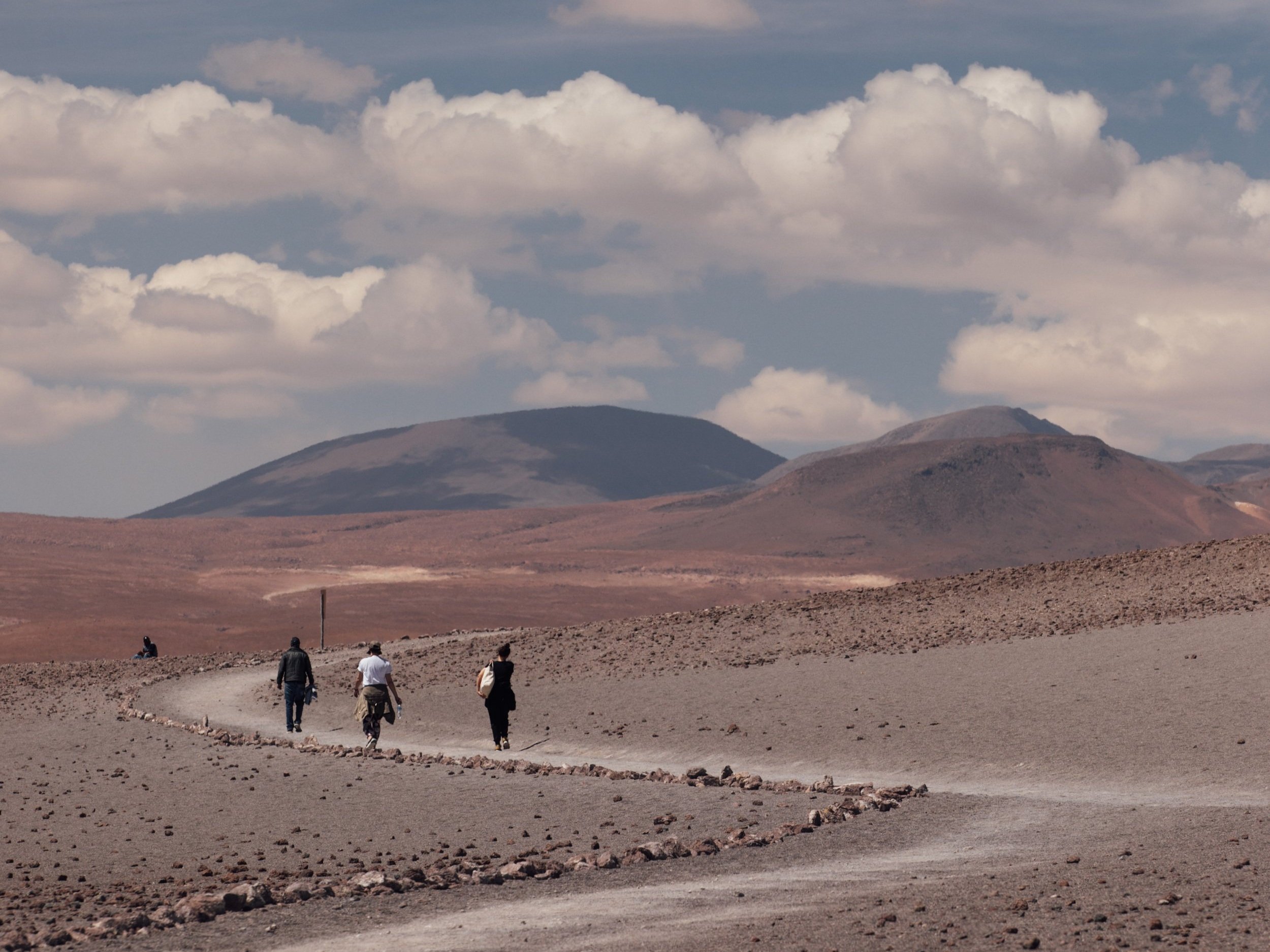 Three women walking on trail toward mountain in Bolivia