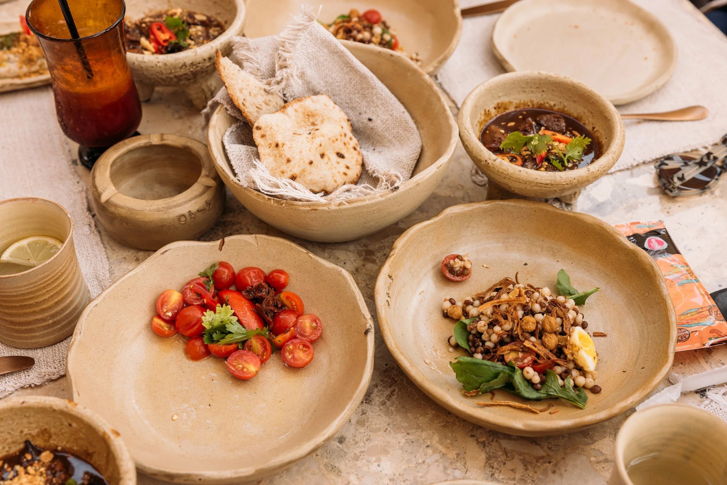 Plates of traditional Egyptian food including tomatoes, chickpeas, pita bread, and soup.