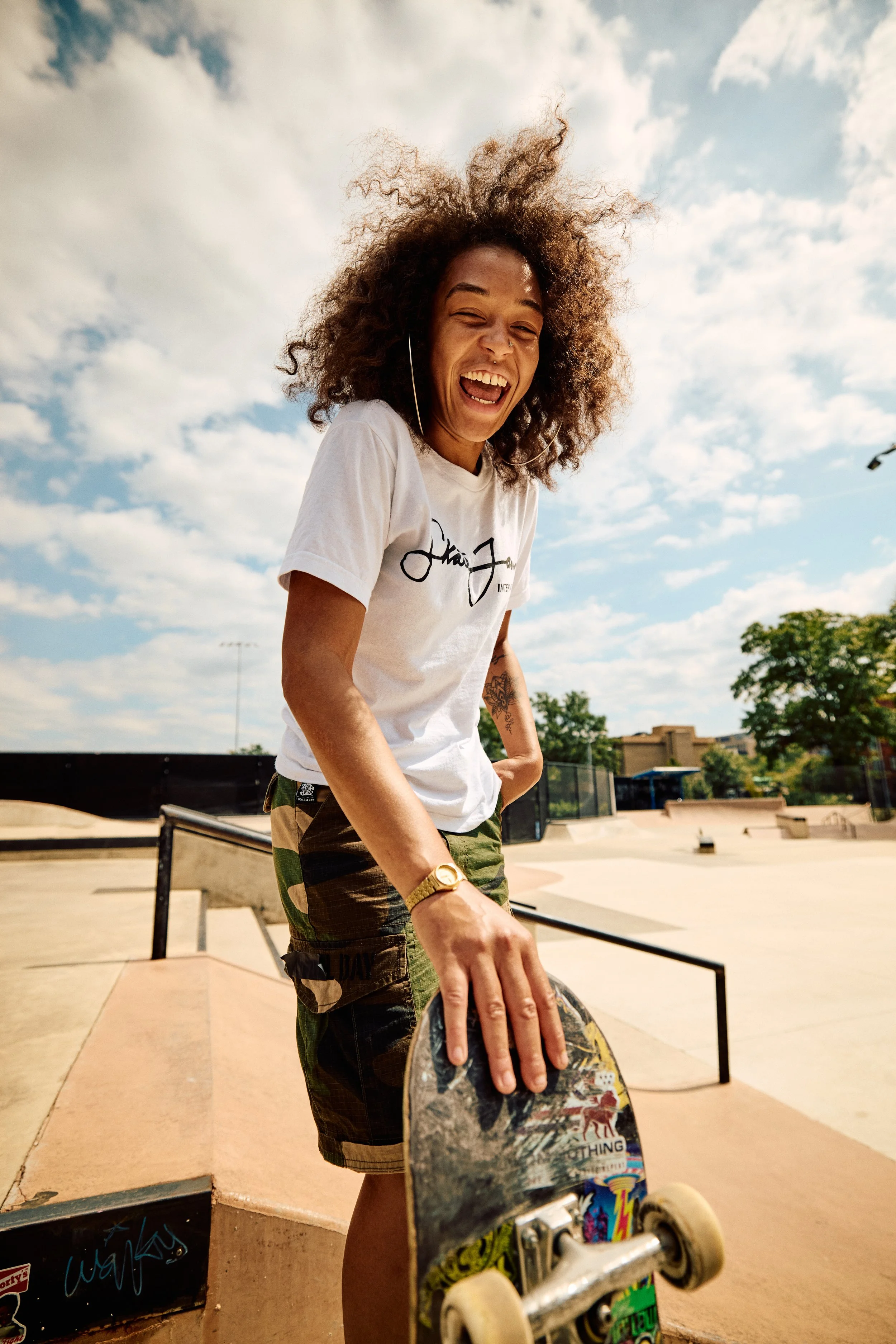 Candid lifestyle photo of skateboarder laughing while holding skateboard at outdoor skatepark in Washington DC