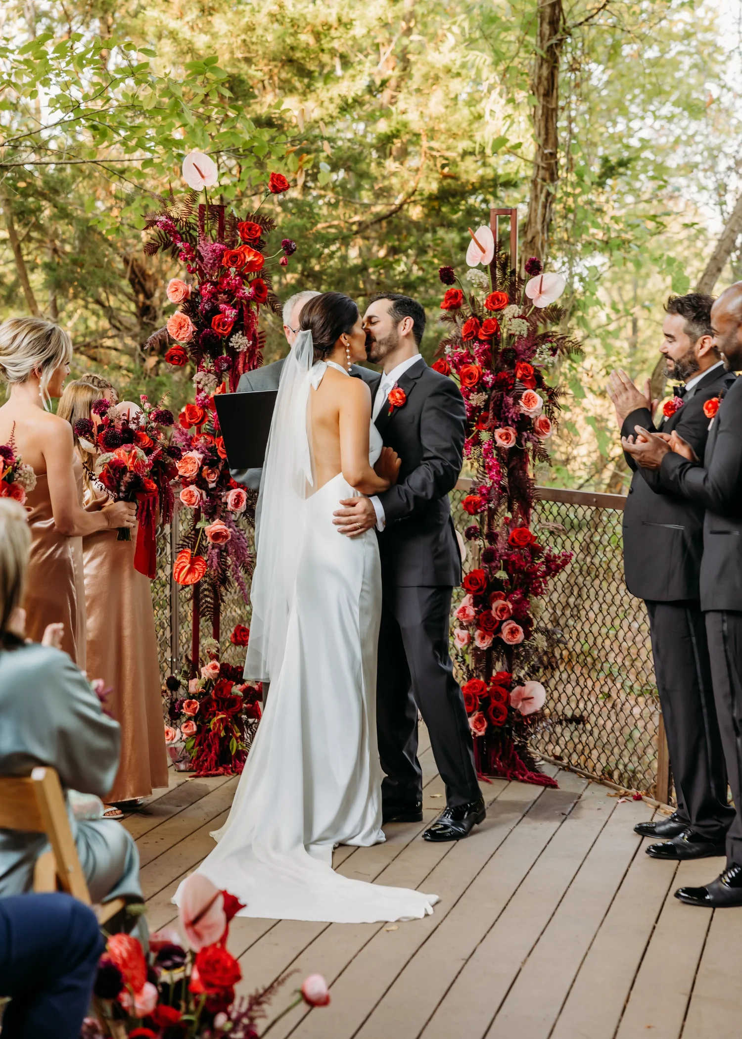 Couple at their ceremony framed by red and burgundy floral pillars