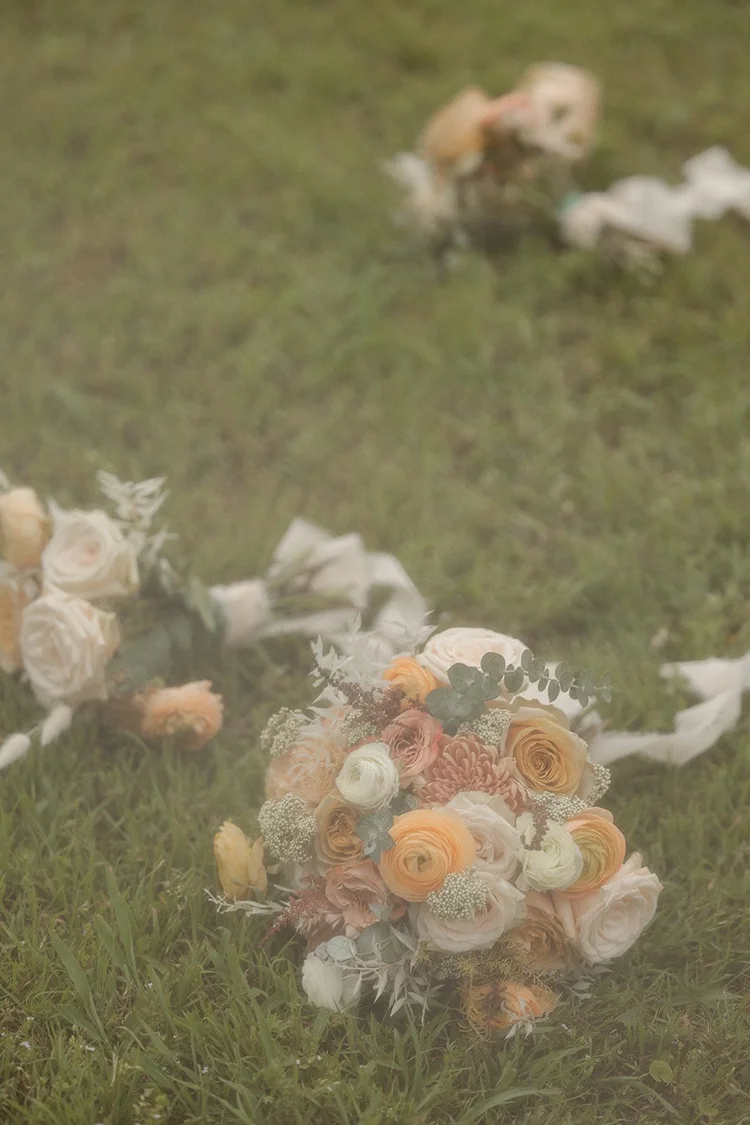 Peach and blush bouquets resting in the grass