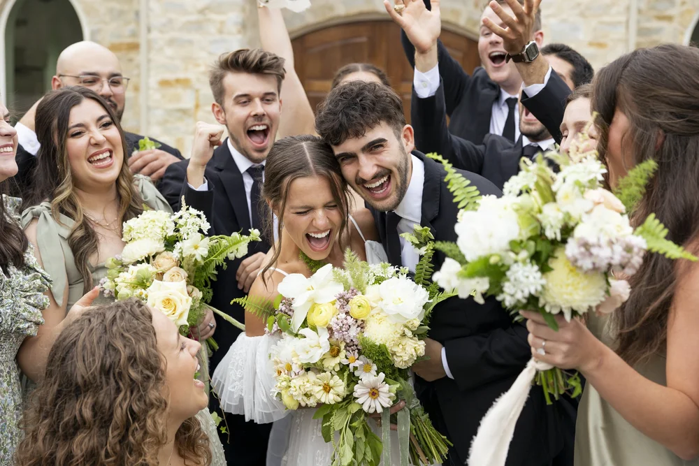 Wedding party celebrating outdoors with the bride's bouquet raised