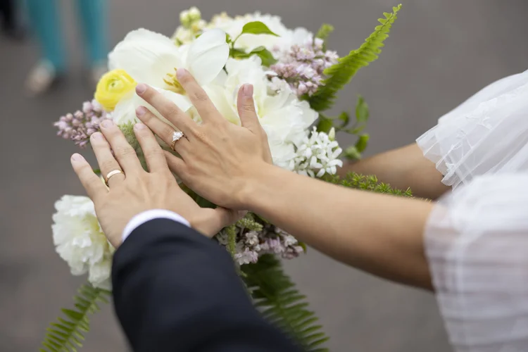 Close-up of hands on a white and yellow bridal bouquet