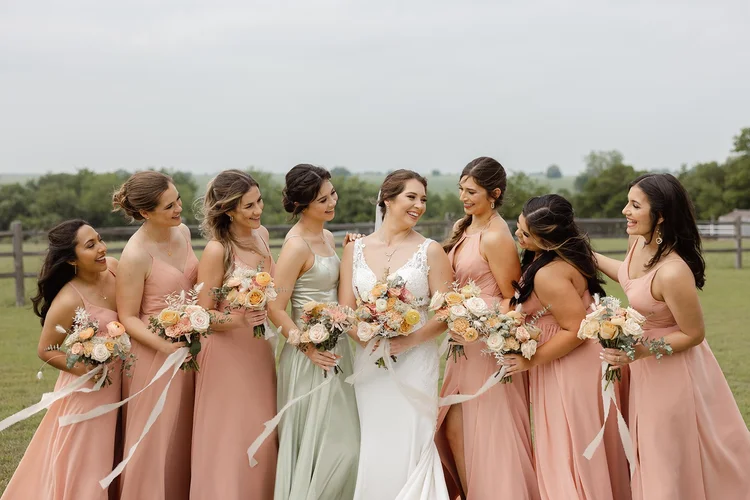 Bridesmaids in peach and sage holding matching bouquets