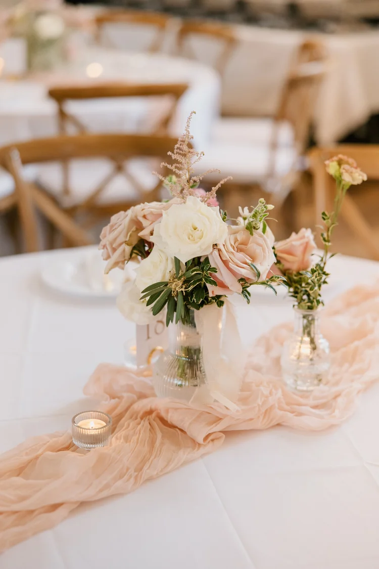 Pink and cream centerpiece in a glass vase on a reception table