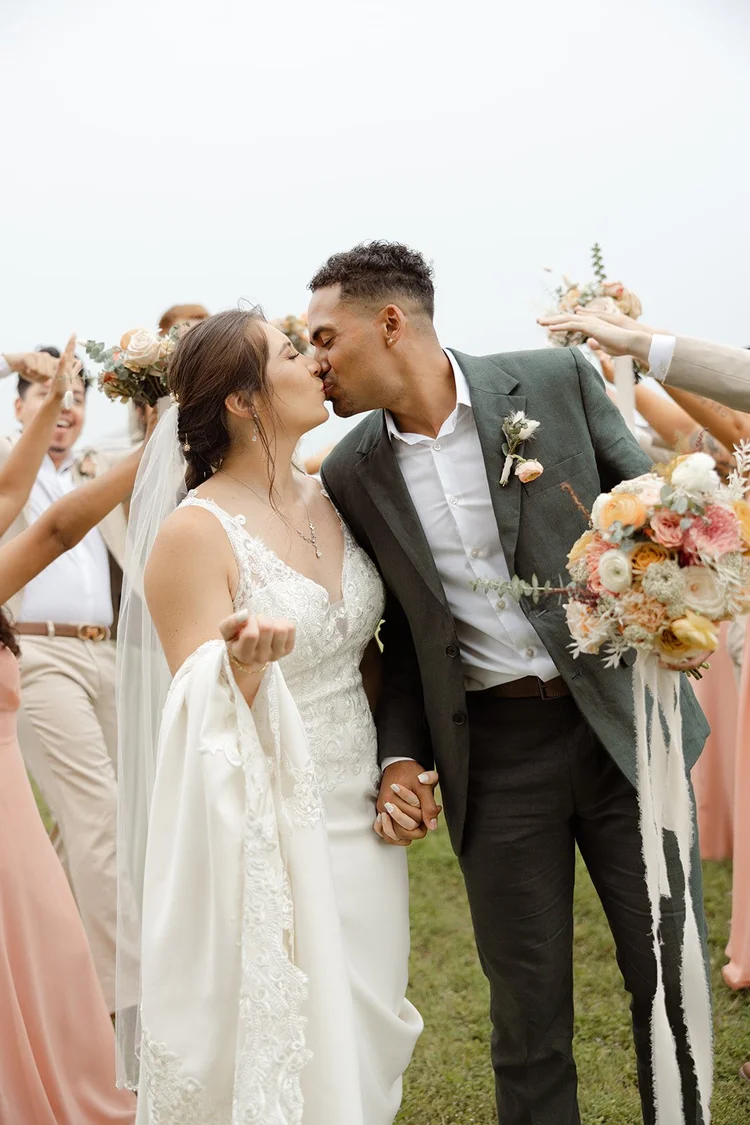 Bride and groom kissing, bouquet in hand