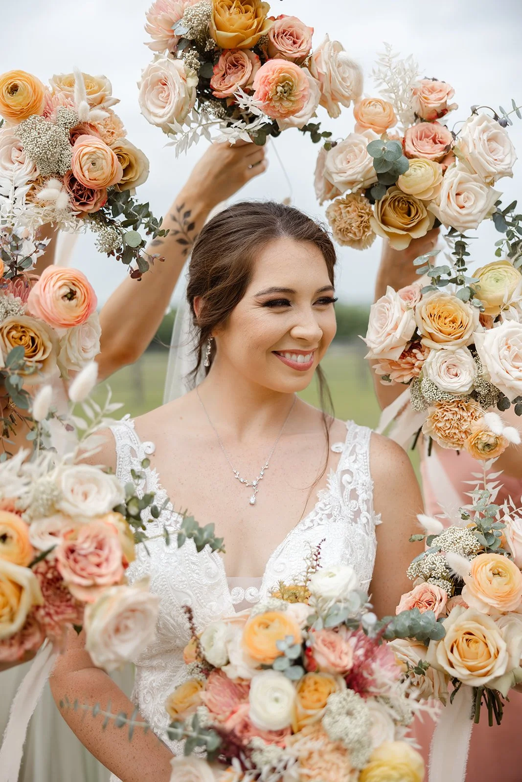Bride smiling, framed by peach and blush bouquets