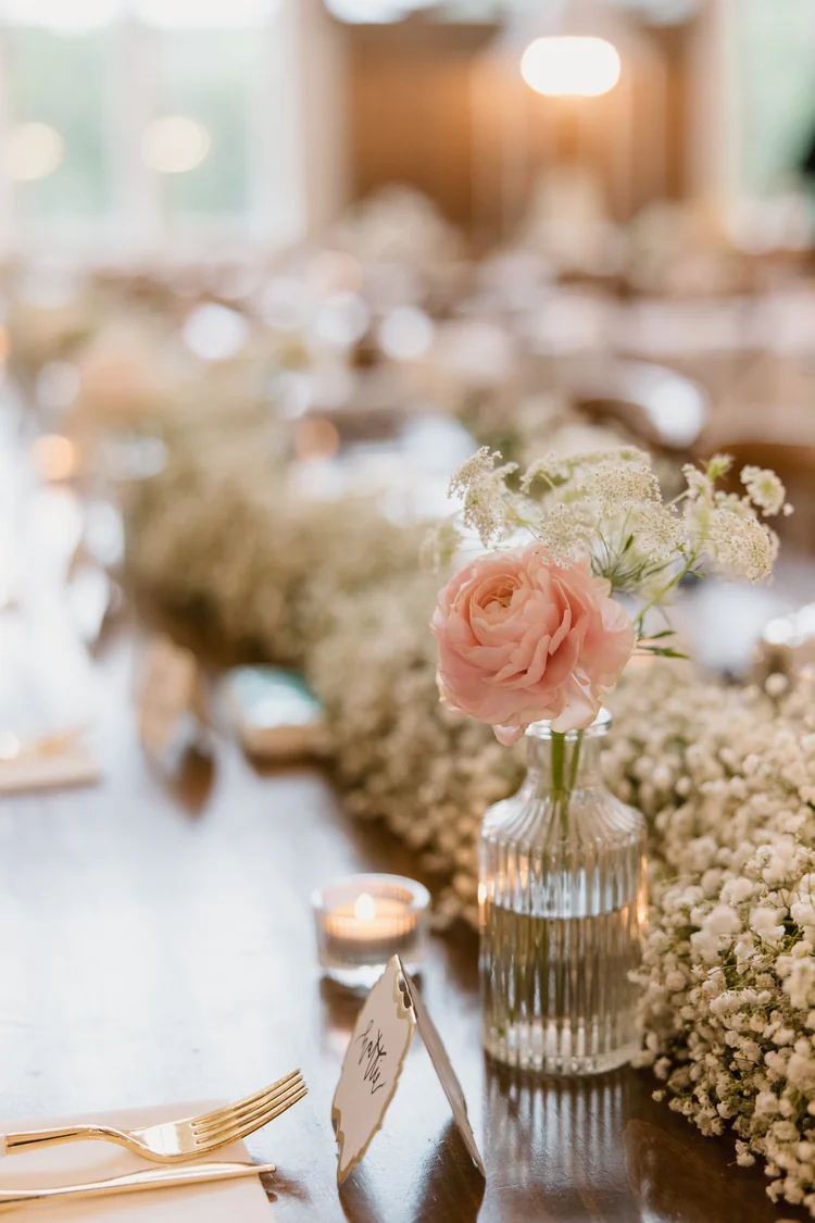 Single peach rose in a bud vase among candles