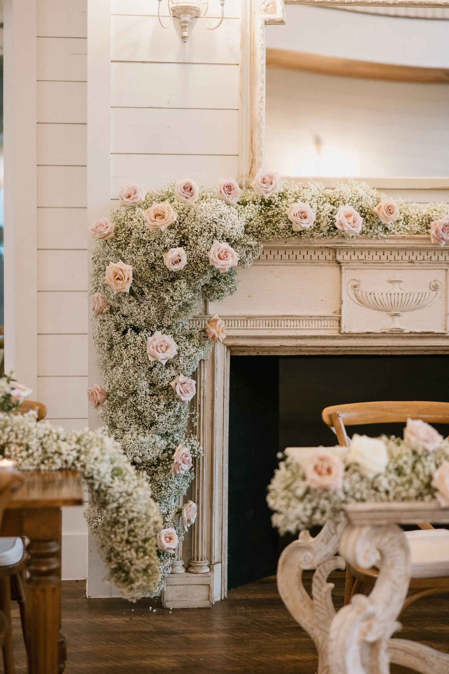 Blush and cream florals cascading over a white fireplace mantel