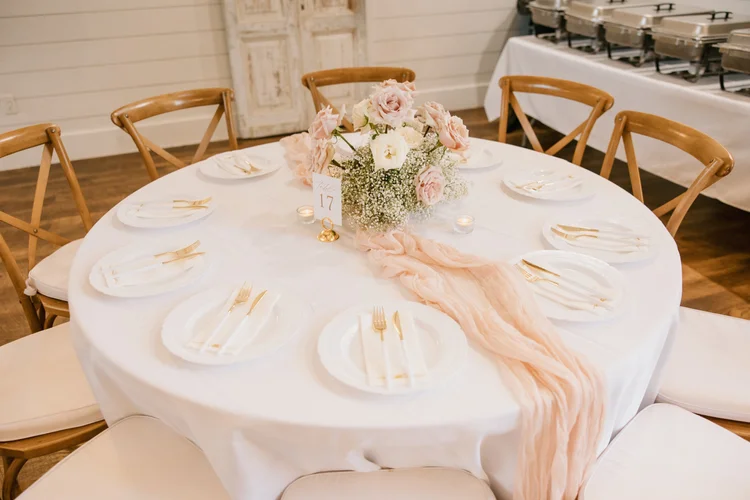Round reception table with a low blush centerpiece and peach runner