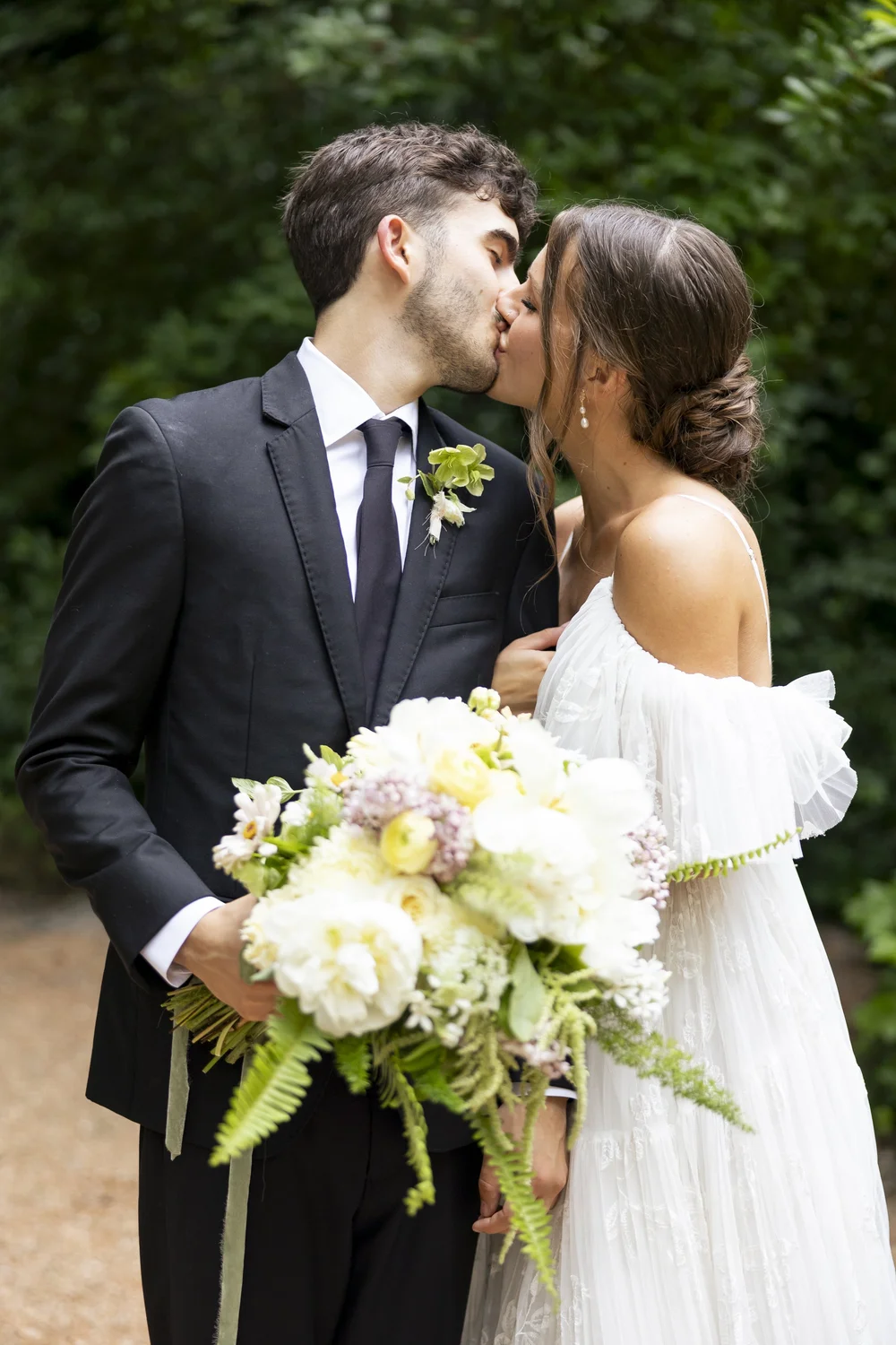 Bride and groom kissing, with her bouquet in hand