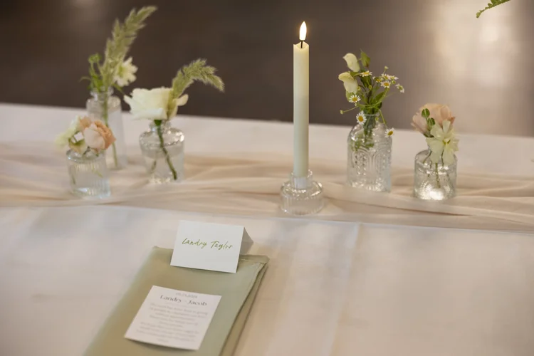 Reception table with bud vases of wildflowers and a taper candle