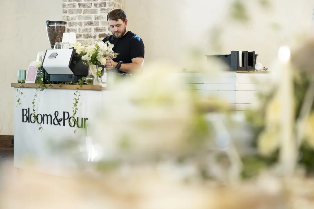 Bloom & Pour barista at the coffee bar, styled with the couple's wedding flowers