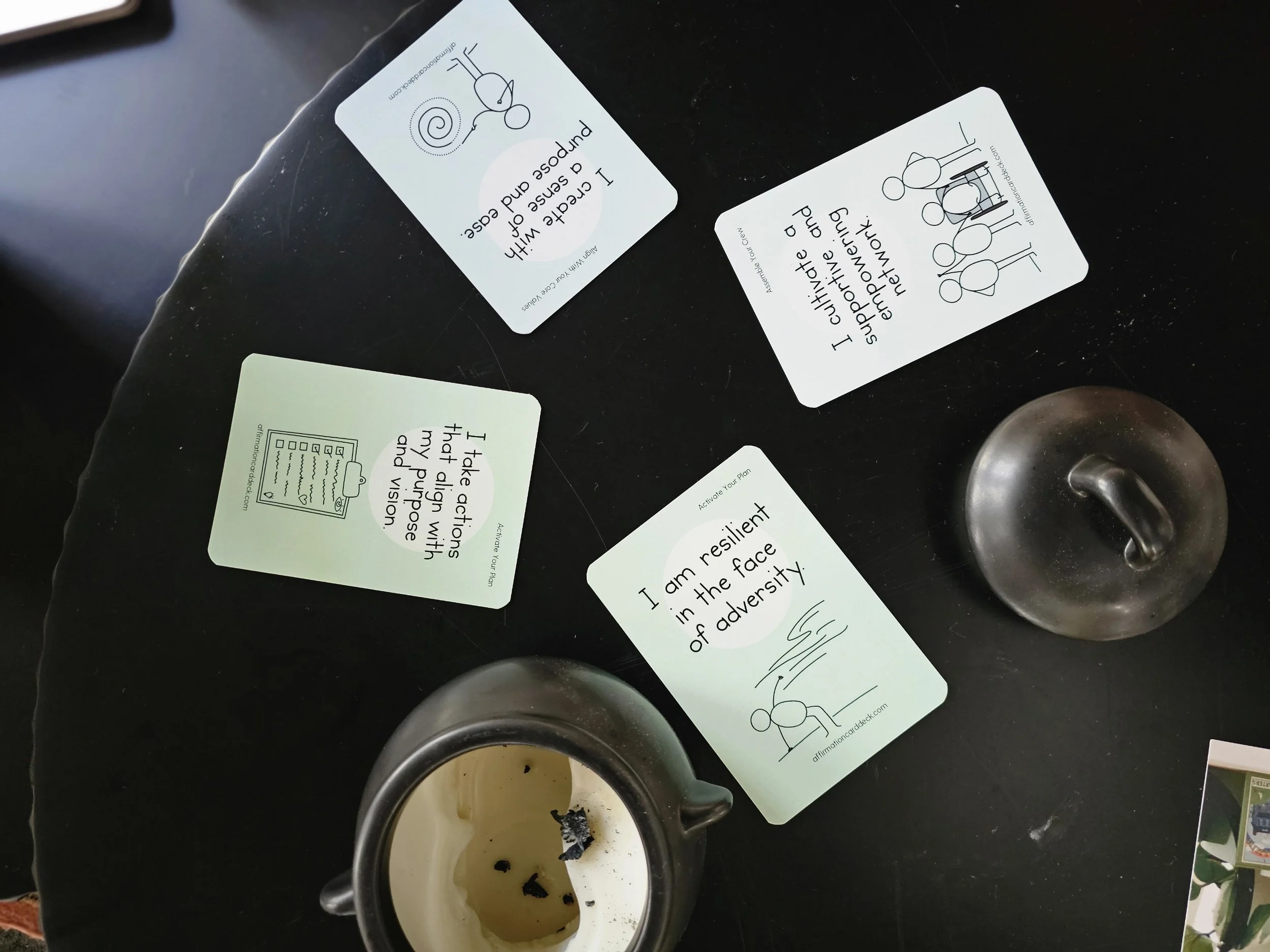 Four Abuntu affirmation cards are laid out on a black table