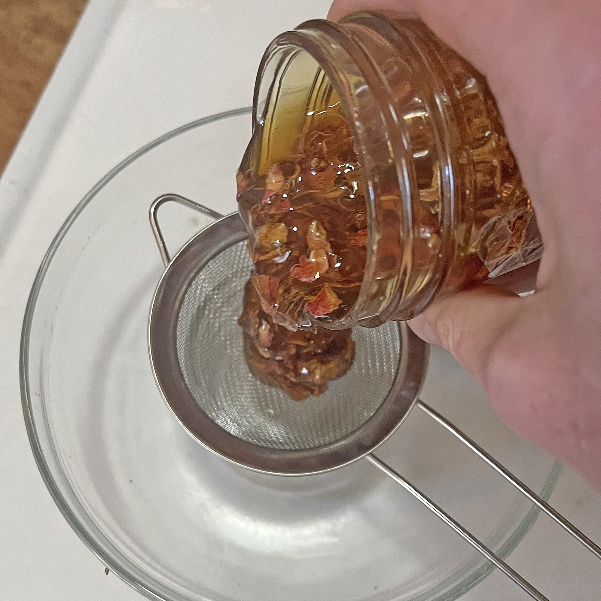 Set the strainer on top of the jar. Pour the honey into the strainer.