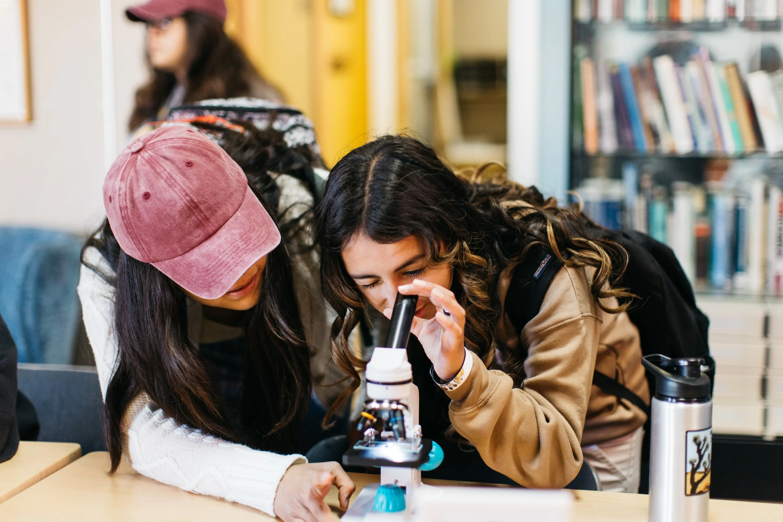 Two young women examine native seeds in a microscope at Mojave Desert Land Trust headquarters in Joshua Tree, California.