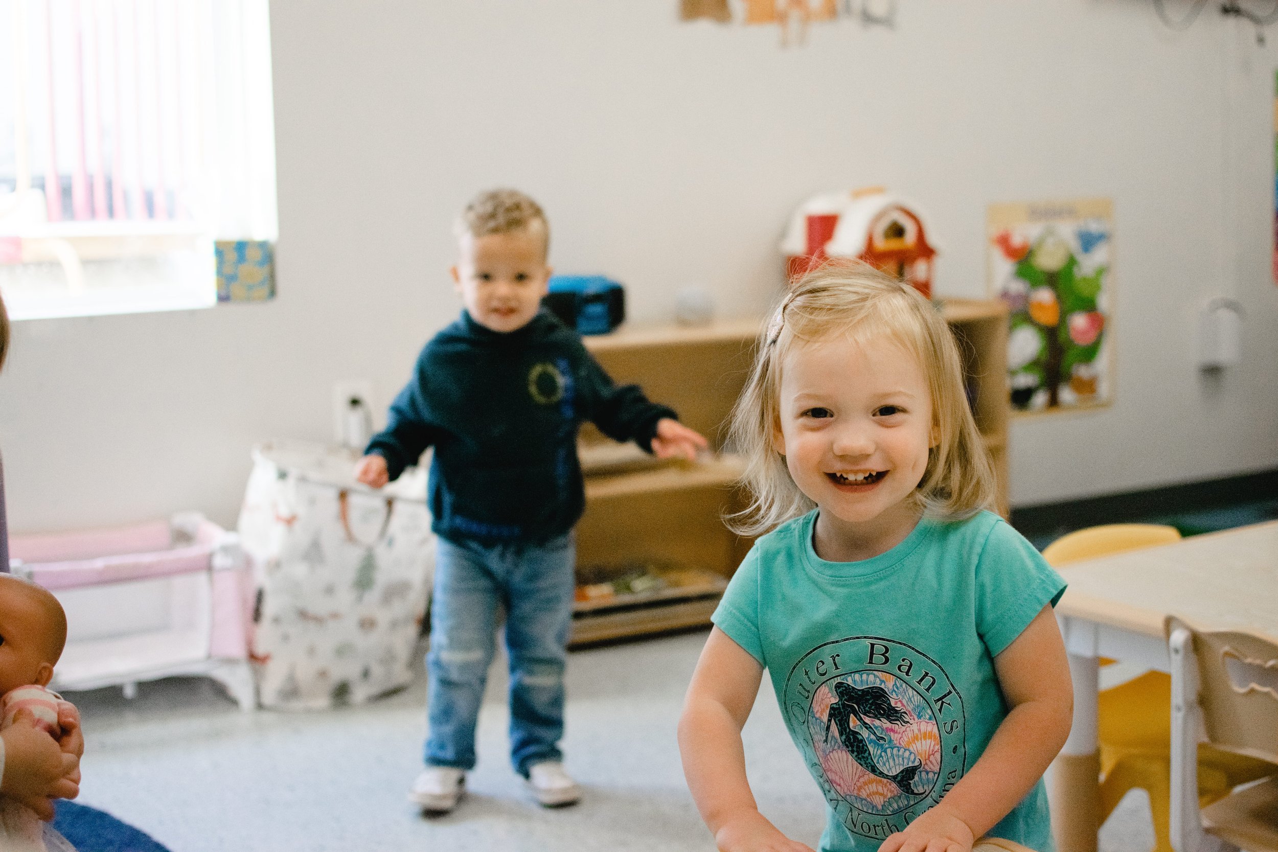 Smiling young girl with blonde hair sitting at a table with children in a classroom. At a private Christian school in Chesterfield and Midlothian