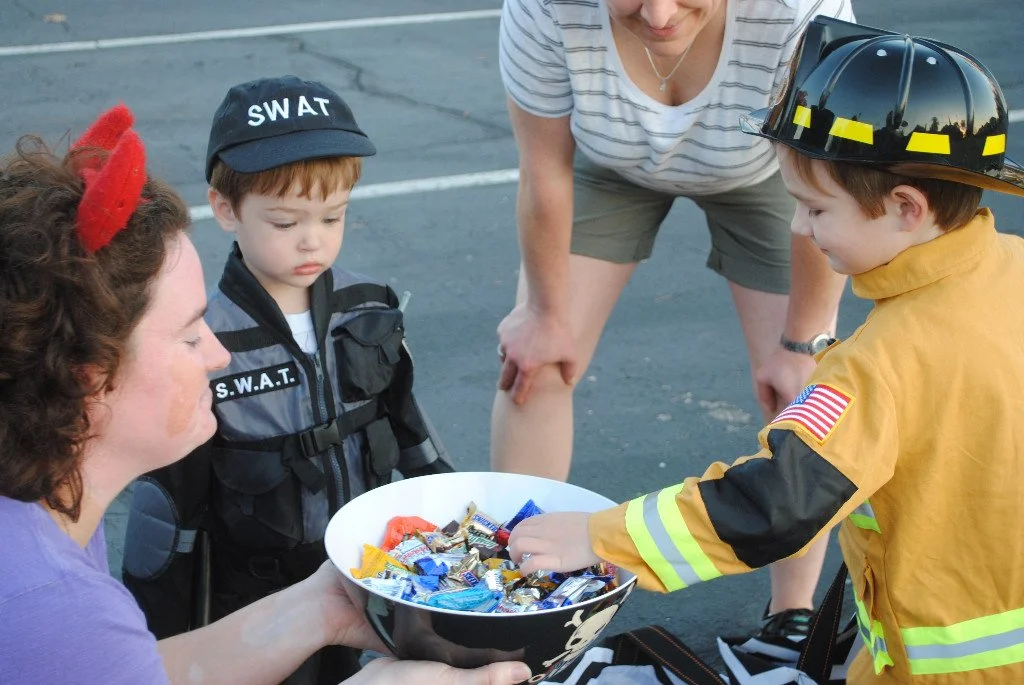 Two children grab candy at a Halloween event