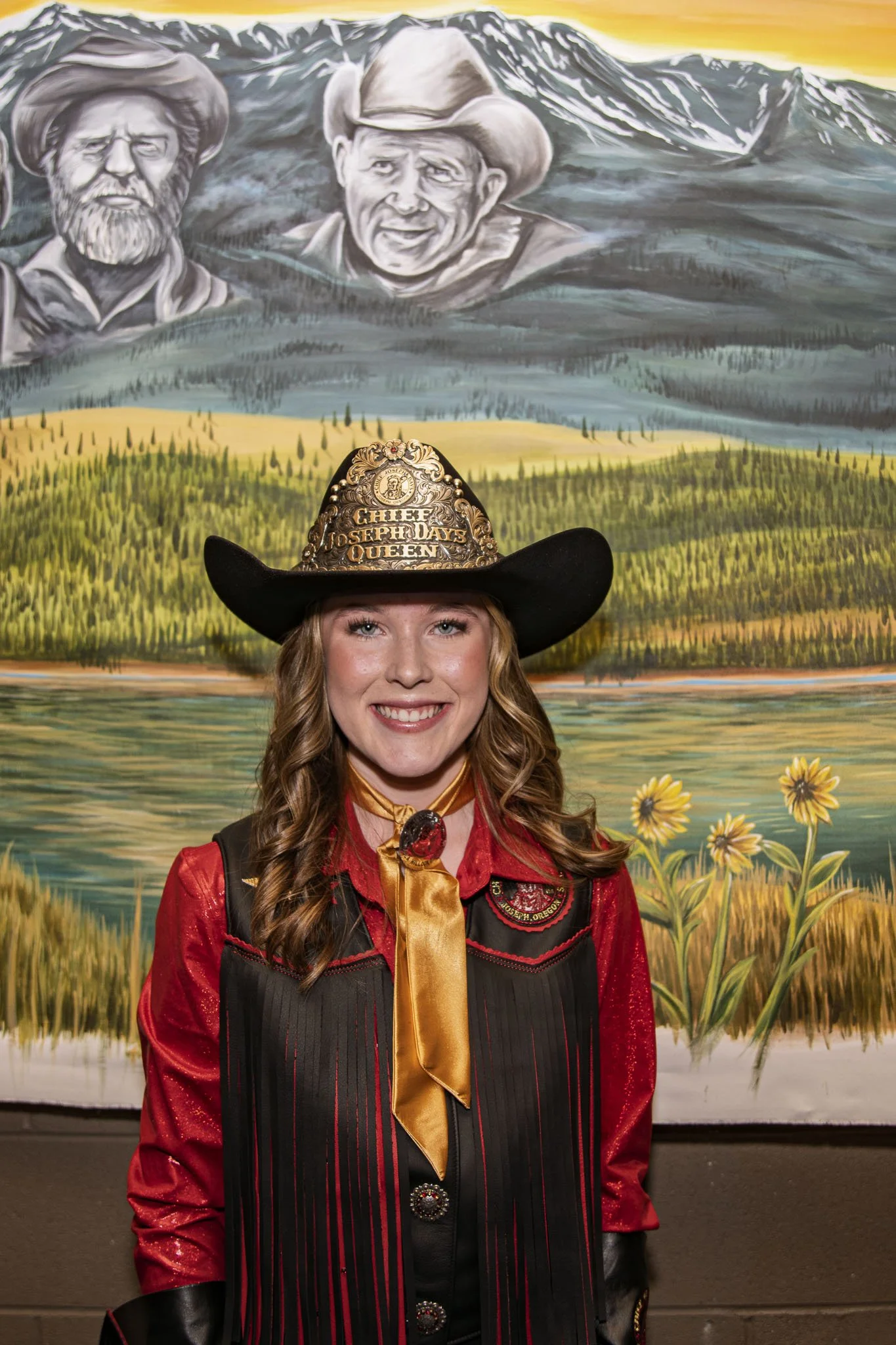 Woman dressed as a rodeo queen with a cowboy hat, blue shirt, and fringed vest.