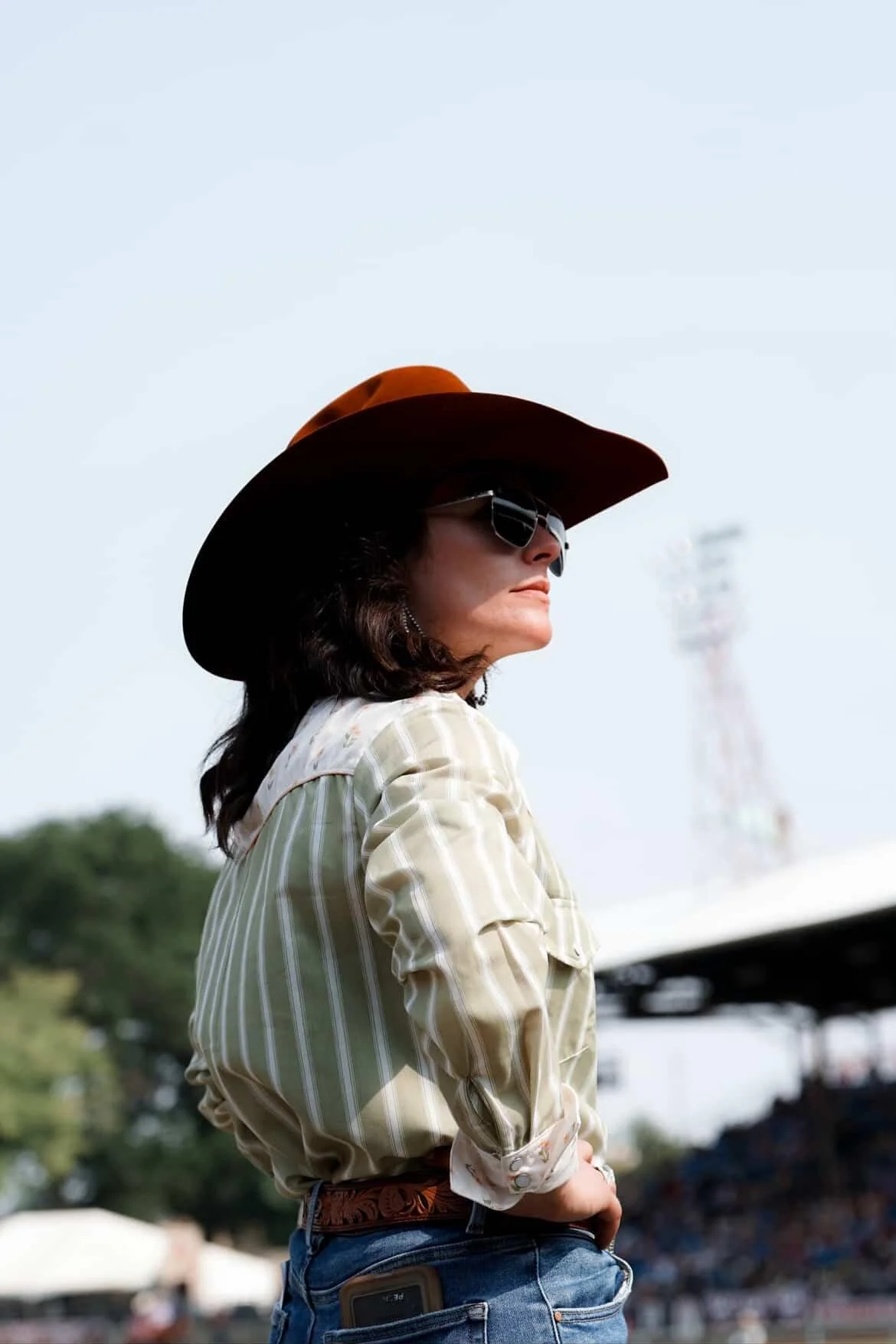 A woman riding a horse at a rodeo, holding an American flag, with a crowd of spectators in the background.
