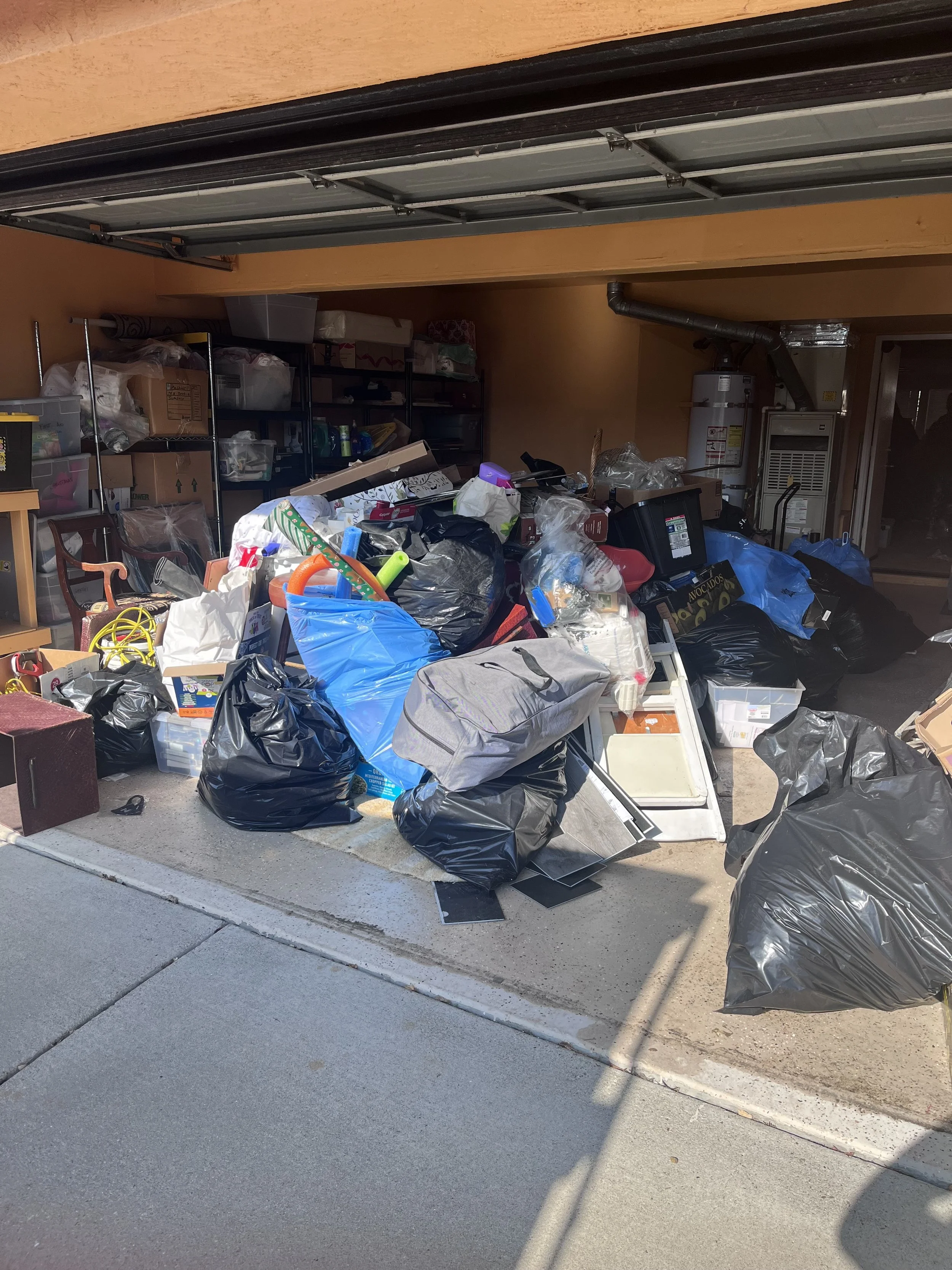 Garage filled with overflowing trash bags, discarded items, and clutter.