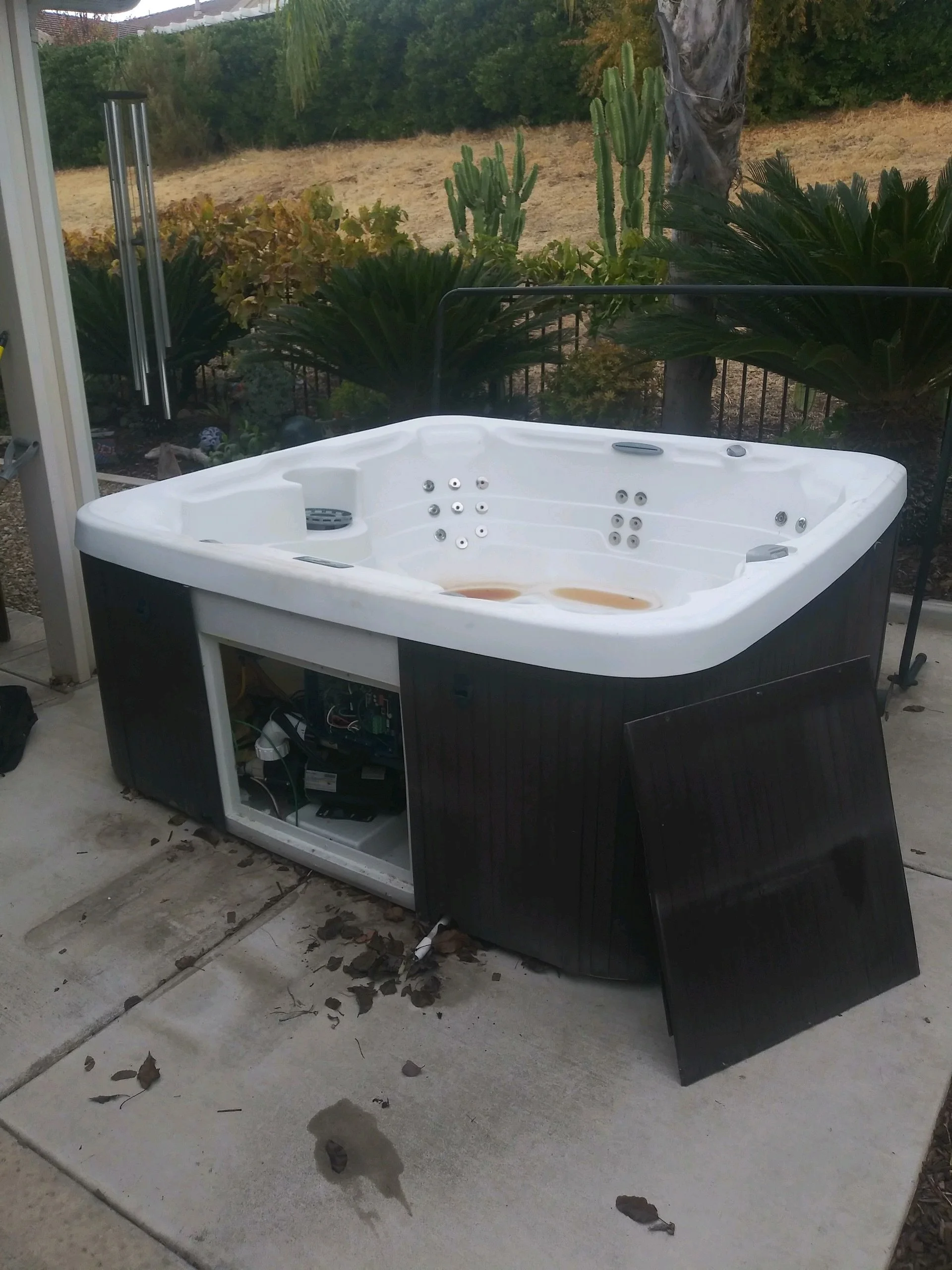 An outdoor hot tub or jacuzzi with the side panel removed, Brentwood hot tub removal, hauling away this old hot tub taking up space on concrete slab. Hot tub removal Brentwood 