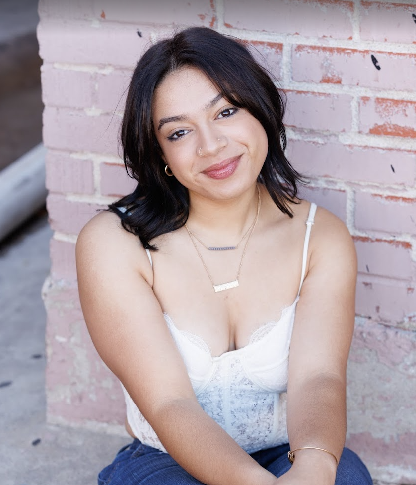 Young lady sits next to brick wall
