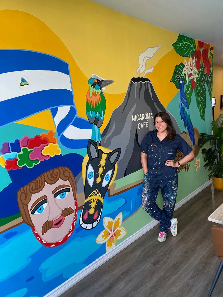 Andreacataro standing in front of a colourful mural inspired by Latin American culture and nature