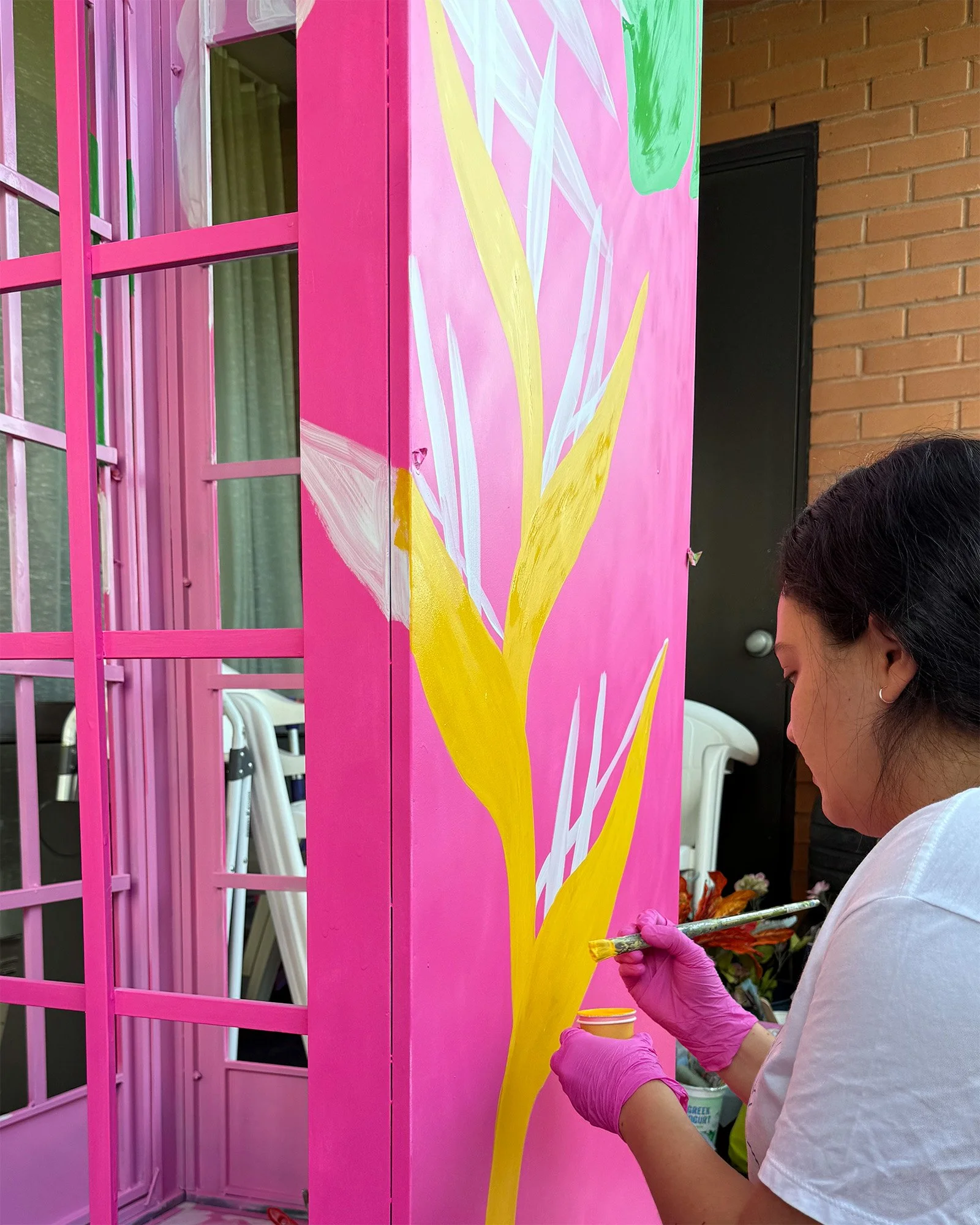 Painting a tropical mural on a metal photo booth structure during a Toronto event project