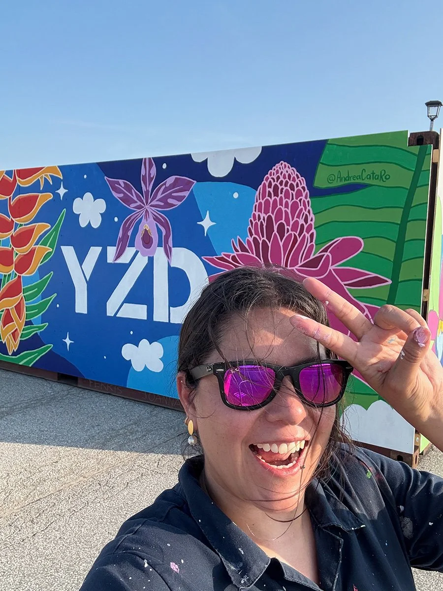 Andrea CataRo, a Colombian Canadian mural artist, on site in front of a colourful public art mural in Toronto
