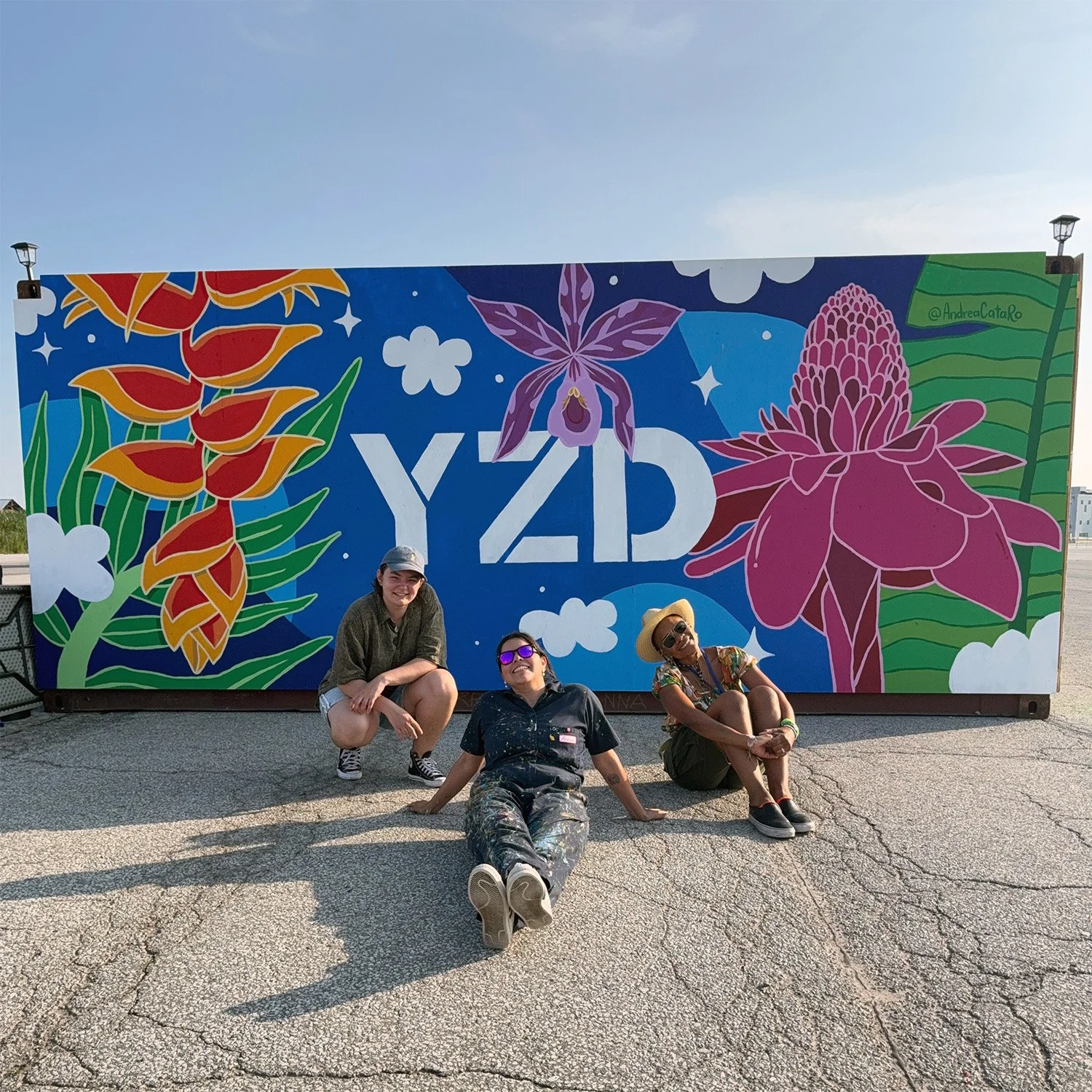 Andreacataro sitting in front of a colourful mural inspired by her Colombian roots in Toronto