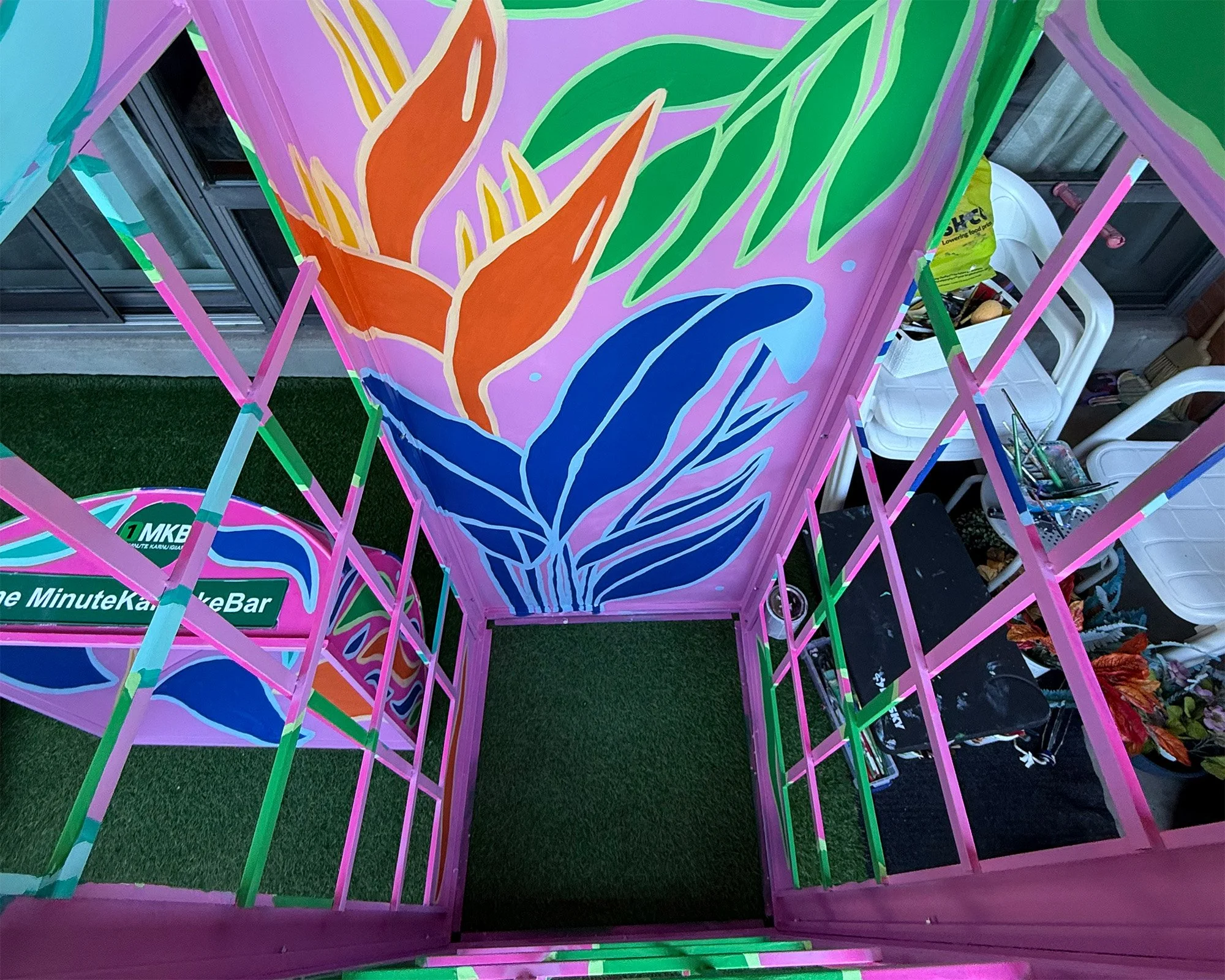 Interior view of a tropical themed photo booth mural painted with pink, blue and green colours in Toronto
