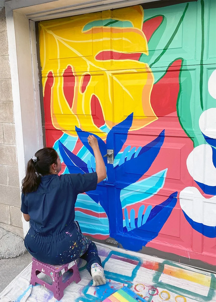 AndreaCataRo painting a colourful community mural in Toronto